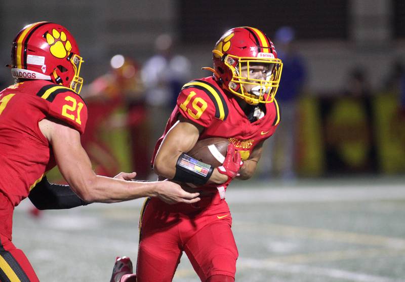 Batavia’s Zach Granberg gets the handoff from quarterback Ryan Boe during a home game against Wheaton North on Friday, Sept. 22, 2023.