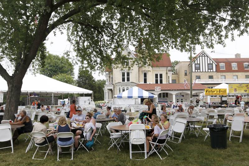 People eat in the shade during Lakeside Festival Friday, June 30, 2023, at the Dole and Lakeside Arts Park in Crystal Lake.