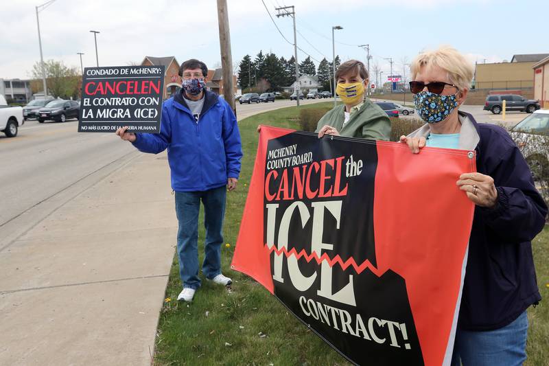 McHenry County Board members Michael Vijuk, left, and Paula Yensen, right, along with Pam Shearman hold signs in favor of canceling the county's contract with U.S. Immigration and Customs Enforcement during a rally at the intersection of Front and West Elm streets on Saturday, April 24, 2021, in McHenry.