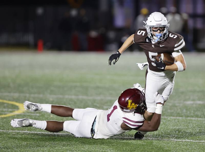 Mt. Carmel's Cooper Lehman (5) is stopped by Loyola's Donovan Robinson (1) during the varsity football game between Loyola Academy and Mt. Carmel high school on Friday, Oct. 25, 2024 in Chicago.