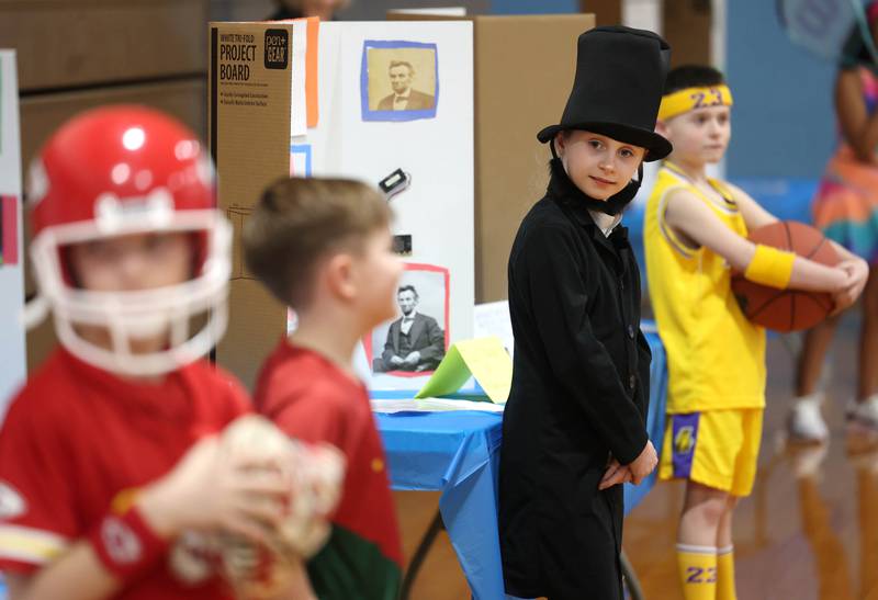 Third grader Ellie Skaggs, playing Abraham Lincoln, checks out some of her classmates costumes as she waits for someone to press the button to activate her speech during the Hinckley Big Rock Elementary School Wax Museum Thursday, March 13, 2025, at the school in Hinckley.