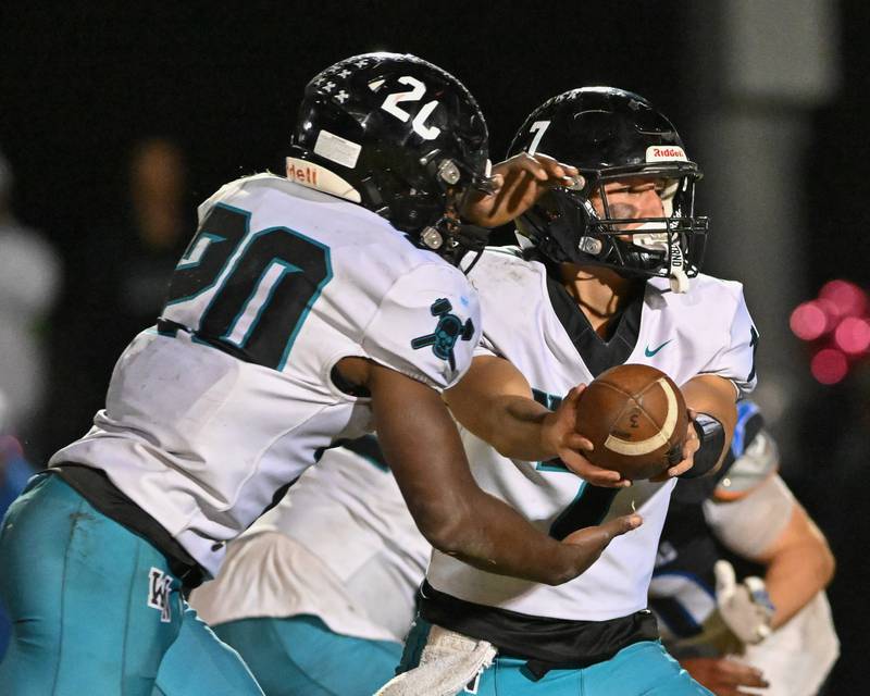 Woodstock North's Parker Halihan hands off to teammate David Randecker against Kishwaukee River Conference and crosstown rival Woodstock on Friday, Oct. 25, 2024 at Woodstock H.S.