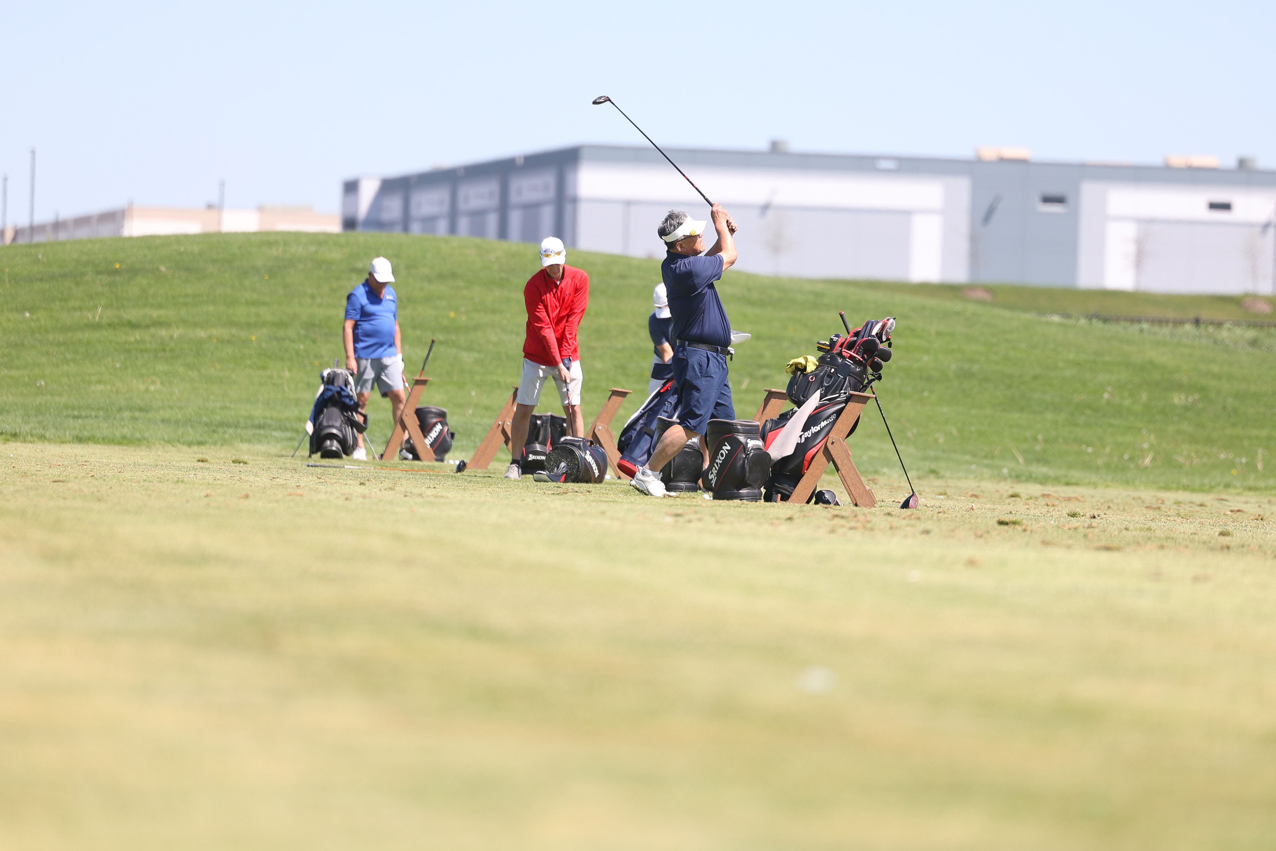 Warehouses sit in the background as golfers practice at the driving range at the Bolingbrook Golf Club on Tuesday, April 30, 2024.
