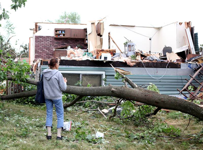 Beverly Sedlacek takes photos of a family friend's home in Woodridge on Monday, June 21, 2021 after it was damaged following a reported tornado late Sunday night, June 20, 2021.