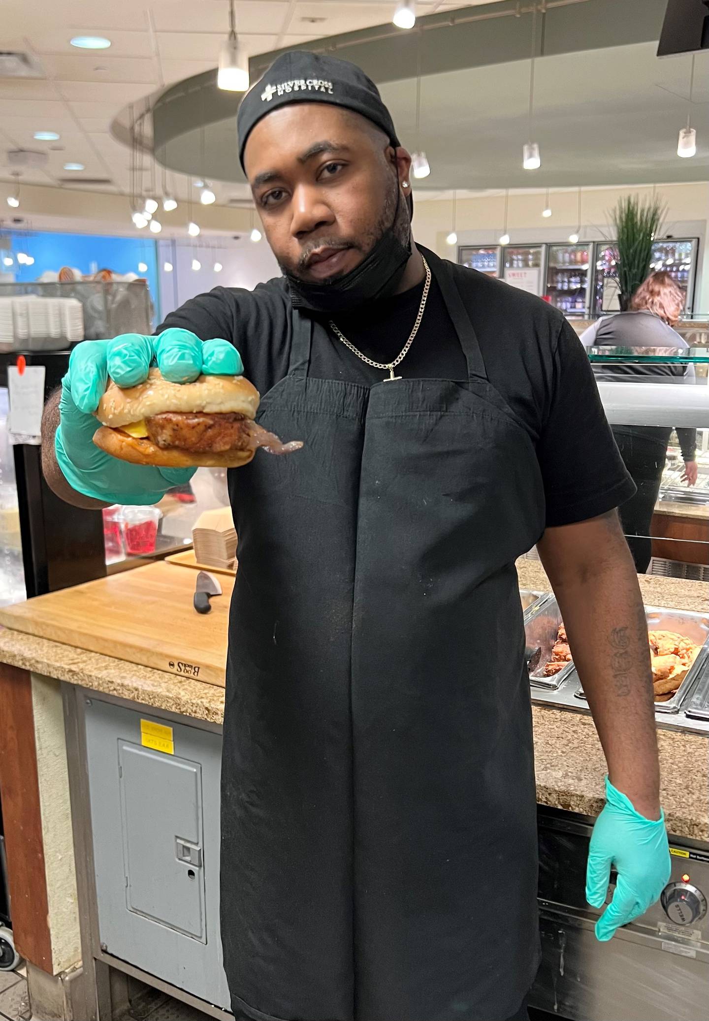 George Funches of Crest Hill shows off the pork tenderloin sandwich he developed for the cafeteria at Silver Cross Hospital in New Lenox. The sandwich consists of a deep-fried pork tenderloin, spicy mayonnaise, grilled onions, American cheese and warmed-up sesame seed bun.