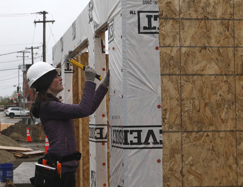 McHenry High School student Kilynn Axelson installs weather wrap on a tiny shop being constructed Monday, May 1, 2023, in the new McHenry Riverwalk Shoppes at Miller Point Park in McHenry. McHenry High School students joined volunteers from Habitat for Humanity, McHenry Parks and Recreation Department, and contractors to build the shops at he site.