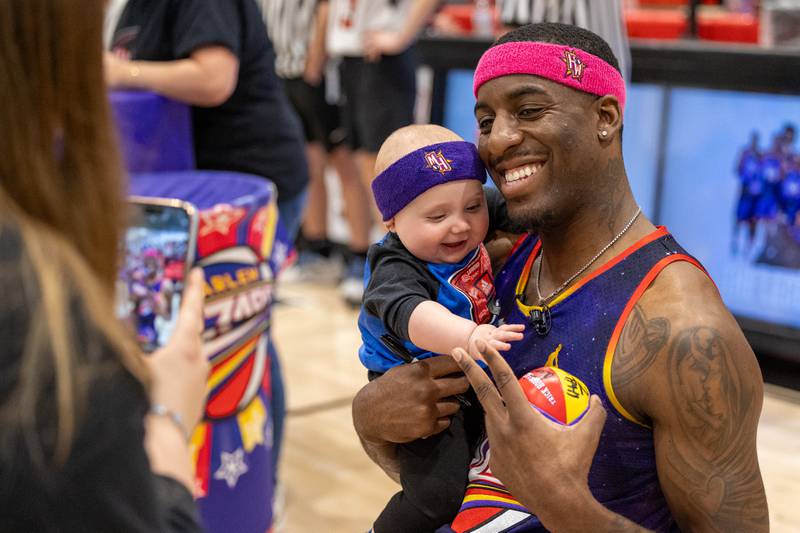 Kamil “Dragon” Brown (77) of the Harlem Wizards takes photo with child on Wednesday, April 16, 2025 at Woodland High School in Streator.