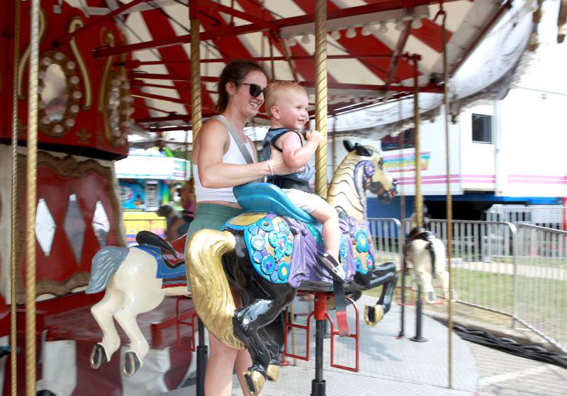 Sam Schneeberger and her son, Noah, 1, ride the carousel on opening day of Swedish Days in Geneva on Wednesday, June 19, 2024.