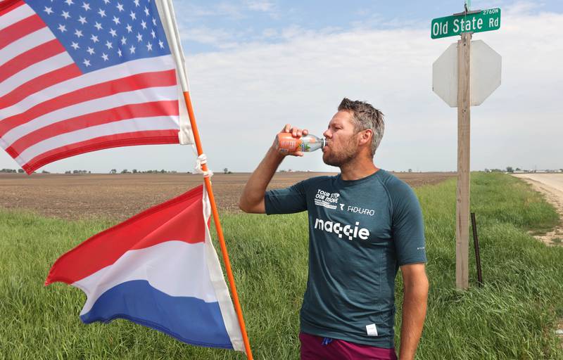 Tom Boerman, from the Netherlands, has a drink and eats lunch during a break from walking Tuesday, May 24, 2022, at the intersection of Old State and Ault Roads near Kirkland. Boerman, who stopped for the night at a home in DeKalb, is on a quest to walk around the world while raising money for schools in Nepal that were hit hard by the 2015 earthquake in the region.