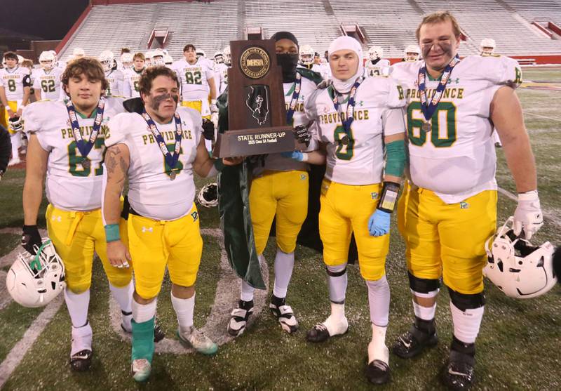 Members of the Providence Catholic football team hoist the Class 5A State runner-up trophy on Tuesday, Dec. 2, 2025 in Hancock Stadium at Illinois State University in Normal.