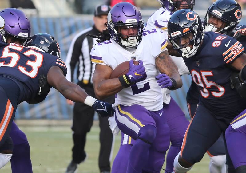 Minnesota Vikings running back Alexander Mattison gets between Chicago Bears linebacker Nicholas Morrow and defensive end Jalyn Holmes Sunday, Jan. 8, 2023, during their game at Soldier Field in Chicago.