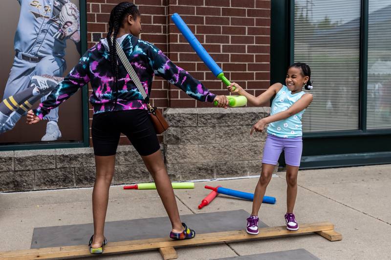 Matteson residents Giselle and Jordyn Carter have a fun lightsaber battle during Joliet Public Library's Star Wars Day event on June 7, 2025.
