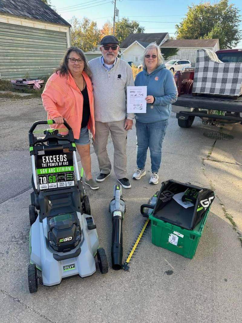 Pictured is Julie Grady, Nedda Simon’s daughter, with her husband Dennis, accepting the raffle prize of an EGO electric mower, trimmer and blower, from Dana VanAutrieve, owner of Johnson’s Carpet. Both organizations received more than $1,500.