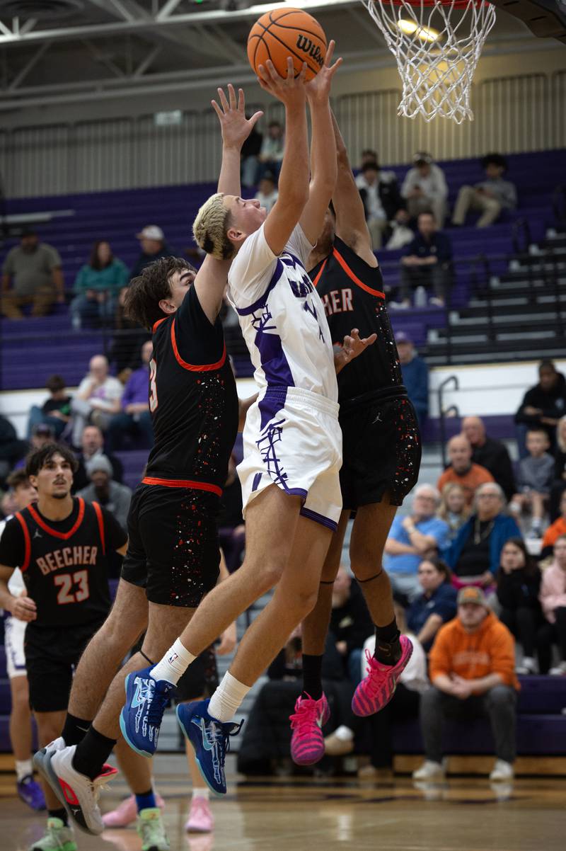 Manteno's Dylan Polito, center, elevates for a shot as Beecher's Kyle Kasput, left, and Wences Baumgartner, right, defend in the Thanksgiving tournament at Manteno High School on Monday, November 24, 2025.