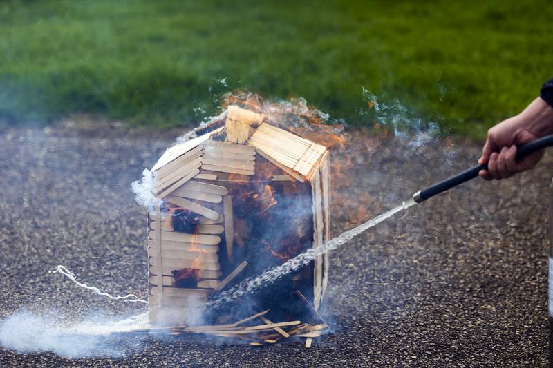 Dixon City Fire chief Ryan Buskohl douses one of the model homes Tuesday, April 22, 2025, at Dixon High School. The forensics class will dismantle the models and learn about fire and smoke patterns to learn about traits of arson.