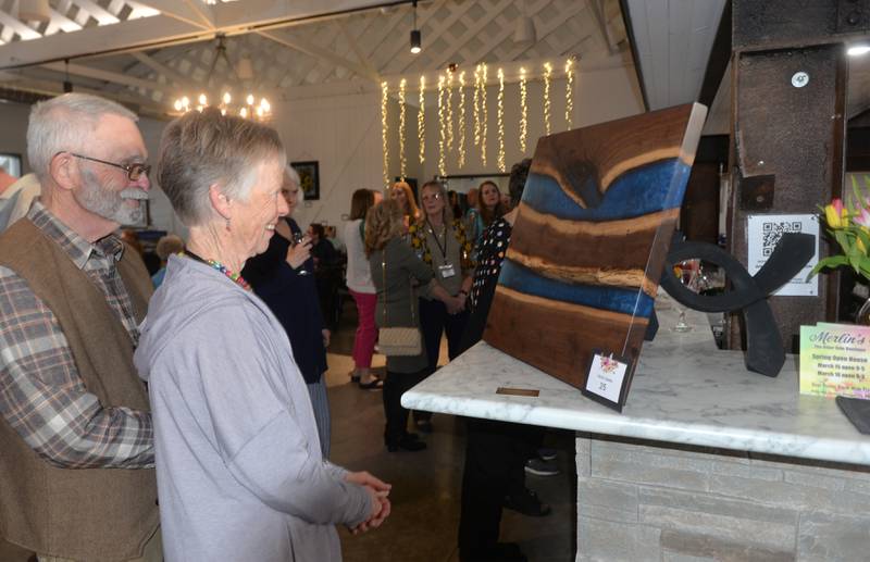 Randy and Nancy Ocken of Polo look at a walnut and blue epoxy table, made by Kevin Deets, at the Art Dash, a fundraiser for Serenity Hospice & Home on Wednesday, April 10, 2024 at River's Edge in Oregon. Nancy also donated art work to the event.