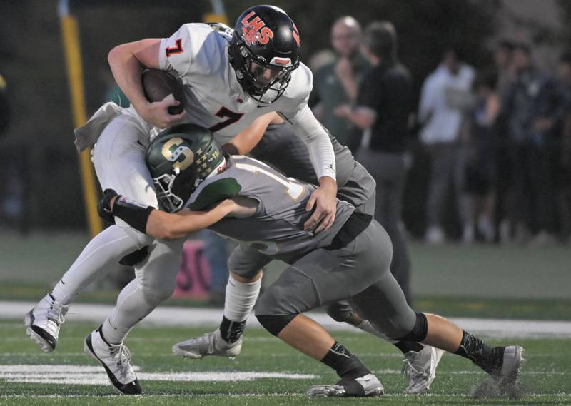 Libertyville quarterback Quinn Schambow is stopped by Stevenson’s Jake Zachara in a football game in Lincolnshire on Friday, Sept. 13, 2024.