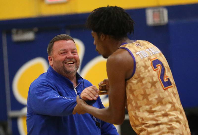 Princeton High School head basketball coach Jason Smith, hi-fives Harlem Wizards player Devale Johnson (Too Tall) during the Harlem Wizards event on Tuesday, Oct. 28, 2025 in Pannebaker Gymnasium at Logan Jr. High School in Princeton. Smith was one of the referees for the event.