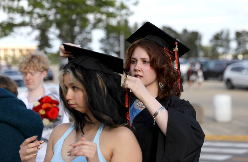 St. Charles East graduate Ashley Hanson helps classmate Izabella Celeste-Wade with her cap before the school’s 2025 commencement ceremony on Thursday, May 22, 2025 at Northern Illinois University in DeKalb.