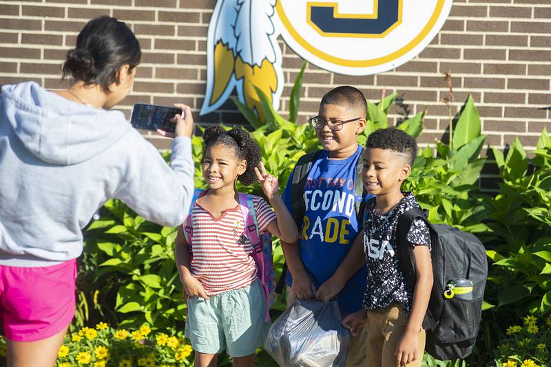 Chynna Parker snaps a picture of Amiyah Parker (left), Emillio Serenil, and Kendrick Parker outside of Jefferson School on Wednesday for the first day of class. Students will start a full day of classes on Thursday.