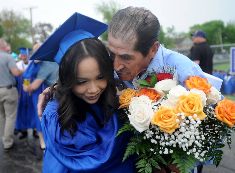 Yenifer Flores is hugged  by her father Gabriel Flores as he giver her flowers Sunday, May 15, 2022, after the Woodstock High School graduation ceremony in Woodstock.