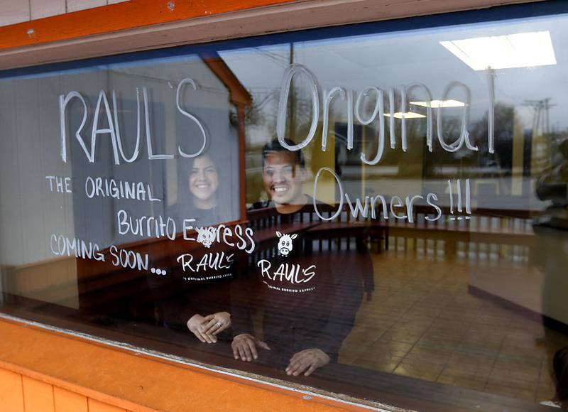 Raul Briseno Jr., and his sister Alexandra Strohmaier, the children of the late Raul Briseno Sr., stand in the front window of their father’s first restaurant on Tuesday, Feb. 22, 2022. They are opening up a restaurant in the original location where their dad opened up his first Raul’s Burrito Express in Wauconda. It has been 21 years since his father was murdered at the Burrito Express he owned in McHenry.
