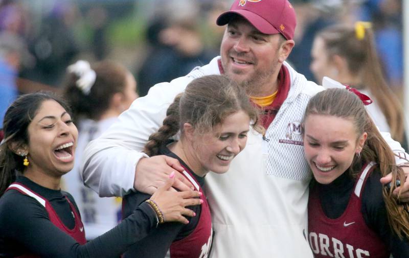 Morris track coach Ryanb Battersby hugs his track players (from left) Gisselle Reyes, Elle McDonald, and Ava Conley after winning the 4x200 meter relay during the Class 2A girls track and field Sectional on Thursday, May 9, 2024 in Princeton.