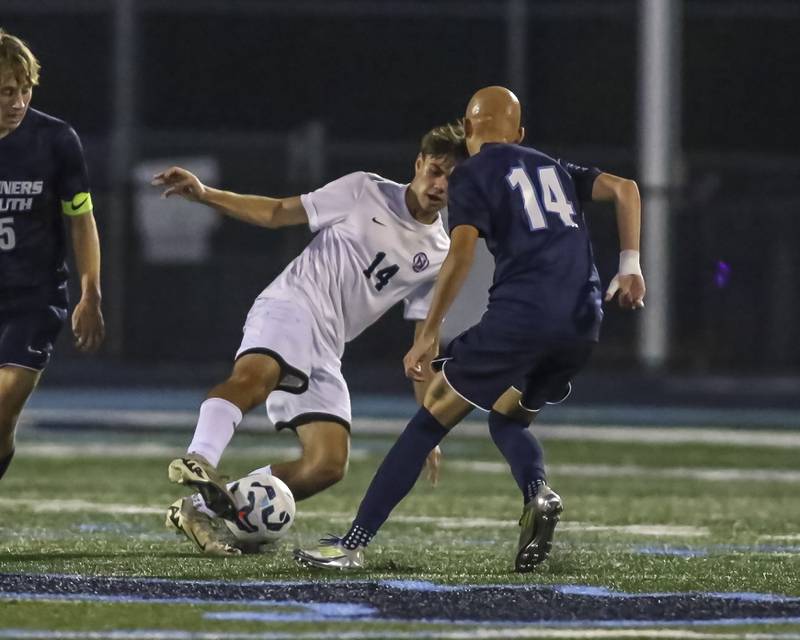 Downers Grove North's Grigore Onica (14) dribbles the ball past the defense of Downers Grove South's Patrick Olczyk (14) during soccer match between Downers Grove North at Downers Grove South. Oct 2, 2025.