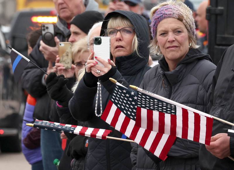 Attendees watch as the processional to Butala Funeral Home honoring DeKalb County Sheriff’s Deputy Christina Musil approaches Monday, April 1, 2024, on DeKalb Avenue in Sycamore. Musil, 35, was killed Thursday while on duty after a truck rear-ended her police vehicle in Waterman.