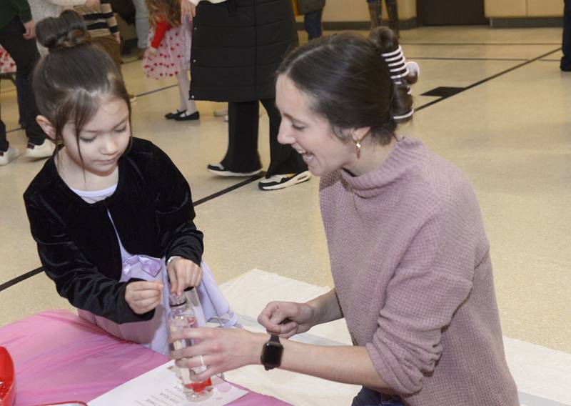 Ellie Steven Martinez has help from Brooke Hassler in creating a glitter globe during a Valentine's Family Fun Day event Friday, Feb. 14, 2025, at Lincoln Elementary School in Ottawa.
