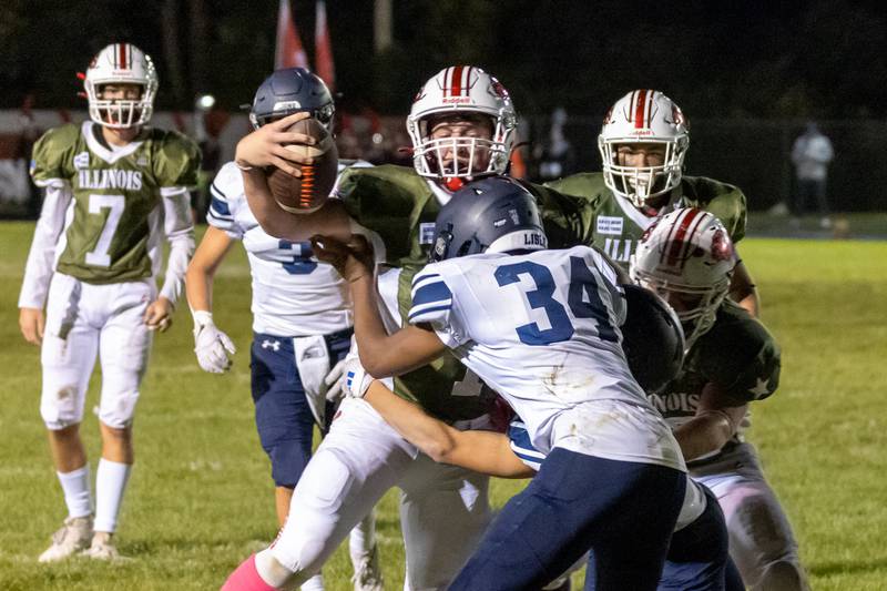 Isaiah Weibel of Streator holds the ball out while being tackled tackled by Patrick Doss of Lisle on Friday, October 4, 2024, in Streator.