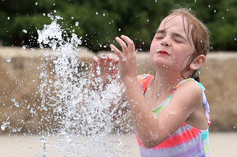 Kids jump through one of the fountains  Thursday, June 20, 2024, at Splash Fountain Splashpad at the Sycamore Park District’s Legacy Campus on Airport Road. High temperatures have been over 90 degrees every day this week making splash pads and pools very popular destinations.