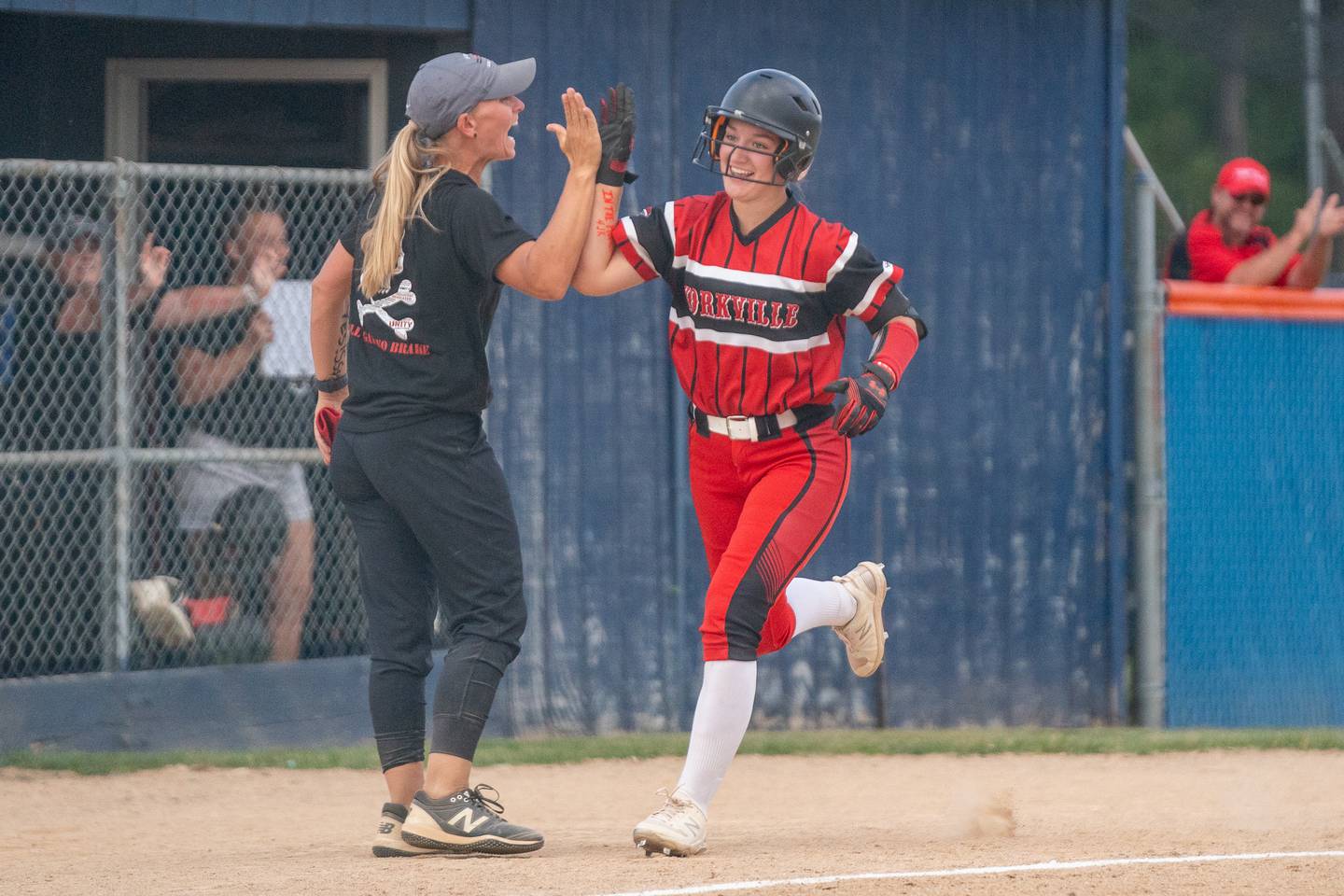 Yorkville's Kaitlyn Roberts (8) rounds third base and gives head coach Jory Regnier a high five after homering against Oswego East during the Class 4A Oswego softball sectional semifinal game between Yorkville and Oswego East at Oswego High School on Tuesday, May 30, 2023.