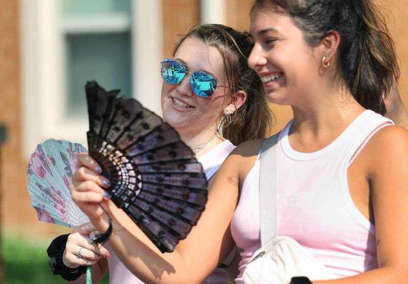 Northern Illinois University sophomore Emily Kemnetz (left) and senior Karla Flores, members of the Delta Zeta sorority, try to keep cool as they volunteer helping students get moved into their dorms Wednesday, Aug. 23, 2023, during move-in day in front of the Fanny Ruth Patterson Complex at NIU in DeKalb.