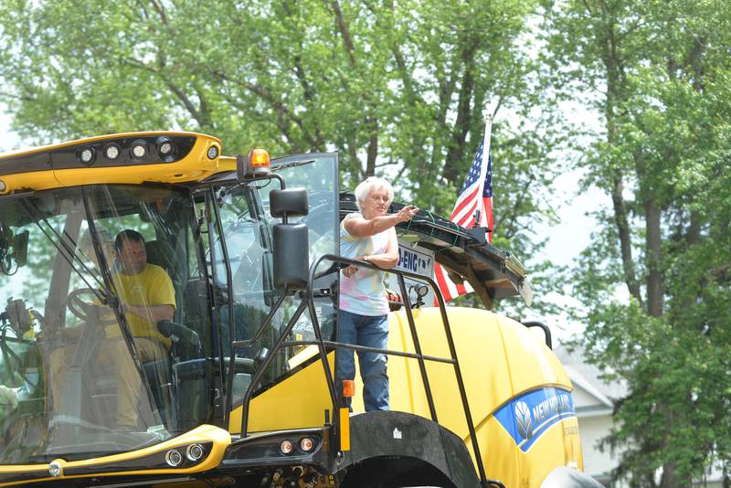 A woman riding on a New Holland combine entered by Jo Eng Dairy Farms of German Valley, tosses candy to the crowd during the Leaf River Daze Parade in Leaf River on Sunday, June 8, 2025.