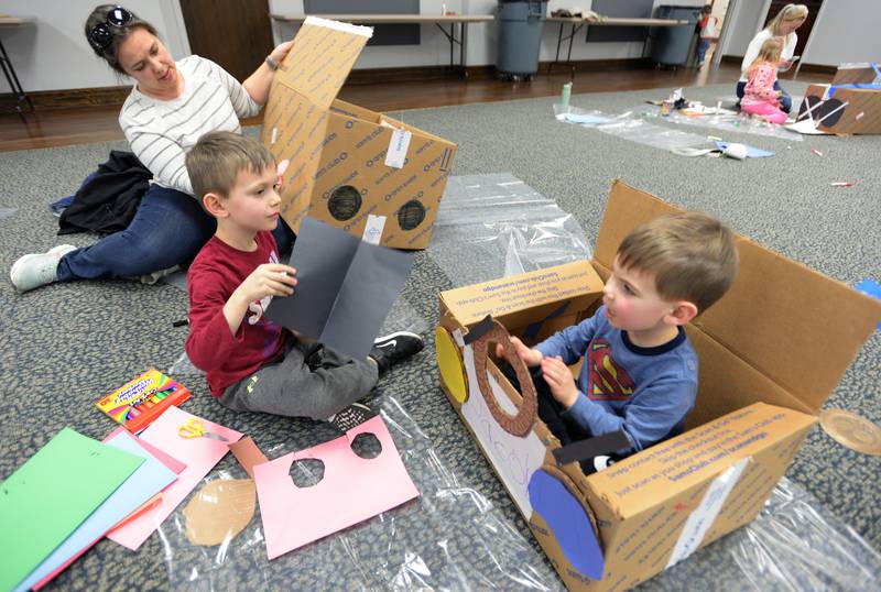 Jacob Hamp sits in his car while Britni Ratliff of LaGrange helps her son (left) Lucas Hamp put the final touches on his car during the Drive In Movie event held at the Park District of LaGrange Friday, Feb 23, 2024.