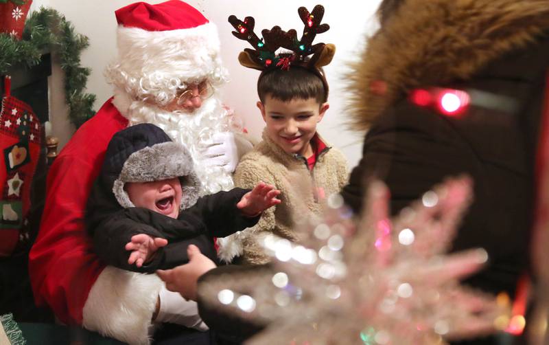 Remington Nuxoll, 1, isn’t happy about meeting Santa for the first time as Kannen Cartee, 5, looks on Friday, Dec. 2, 2022, during Celebrate the Season hosted by the Genoa Area Chamber of Commerce.