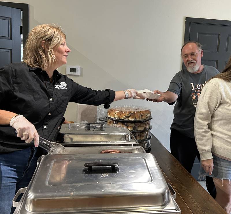 Oregon Park District Superintendent of Recreation, Tina Ketter, hands a hot dog to John Miller of Rochelle during Oregon's National Night Out and Touch-A-Truck event on Tuesday, Aug. 6, 2024. The event was hosted by the Oregon Police Department and park district at River's Edge Experience.