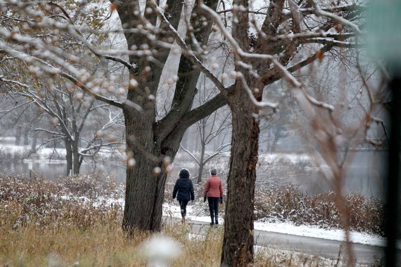The first snow of the season falls around a pair of walkers at Fabyan West in Geneva on Tuesday, Nov. 15, 2022.