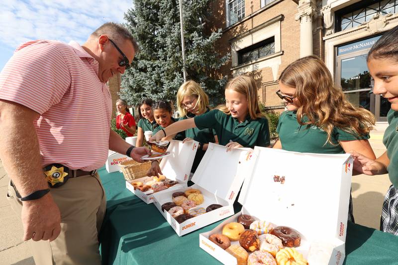 Bishop McNamara Catholic School fifth grader Allie Quigley hands a donut to Kankakee County Undersheriff Chad Gessner as she and her fellow student council members host the 10th Gratitude Drive-Thru for first responders and military members on Thursday, Sept. 11, 2025.