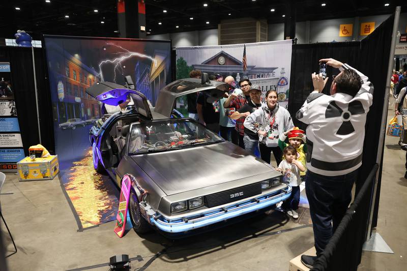 A group poses for a photo with the icon Delorean time traveling car, from the movie Back to the Future, at C2E2 Chicago Comic & Entertainment Expo on Saturday, April 1, 2023 at McCormick Place in Chicago.