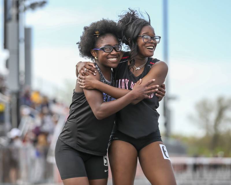 Oswego East's Layla Brisbon (L) is congratulated by Bolingbrook's Quanesha Williams in her 100m hurdles win during Southwest Prairie Conference Girls Track and Field Meet Wednesday, May 7, 2025 in Minooka.