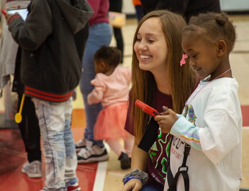 An NIU student volunteer helping a child fly a drone at STEM Fest
