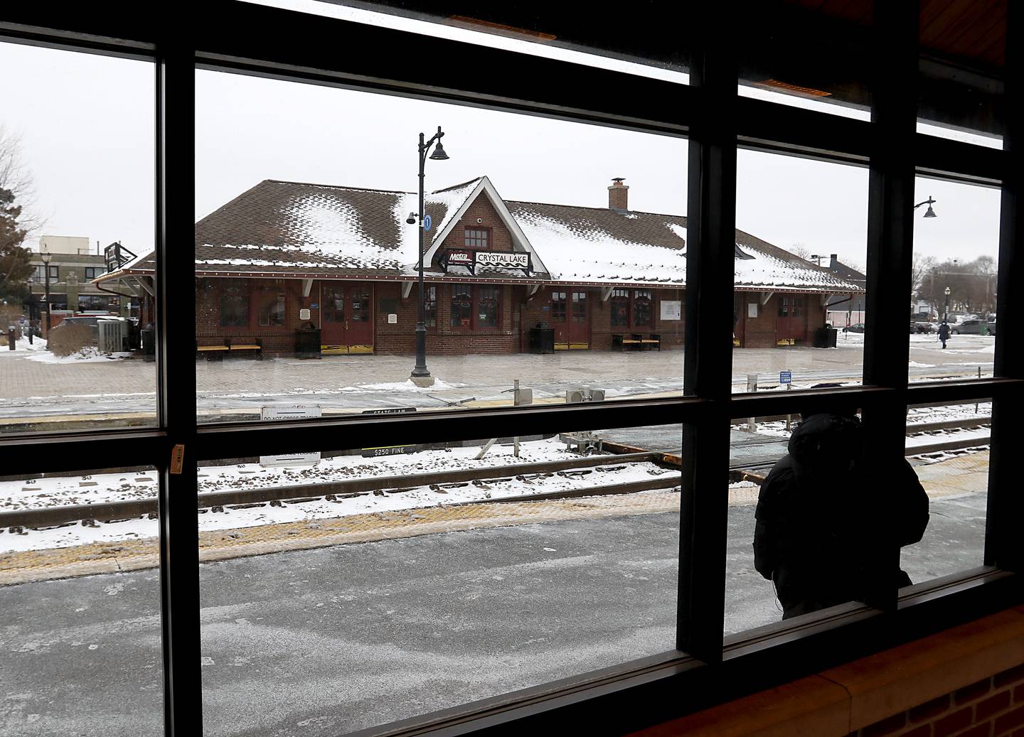 A woman waits for a train Thursday, Feb, 3, 2022, at the Metra station in downtown Crystal Lake. Crystal Lake and Cary are in the considering purchases their downtown stations after Union Pacific decided to sell this station and other commuter stations.