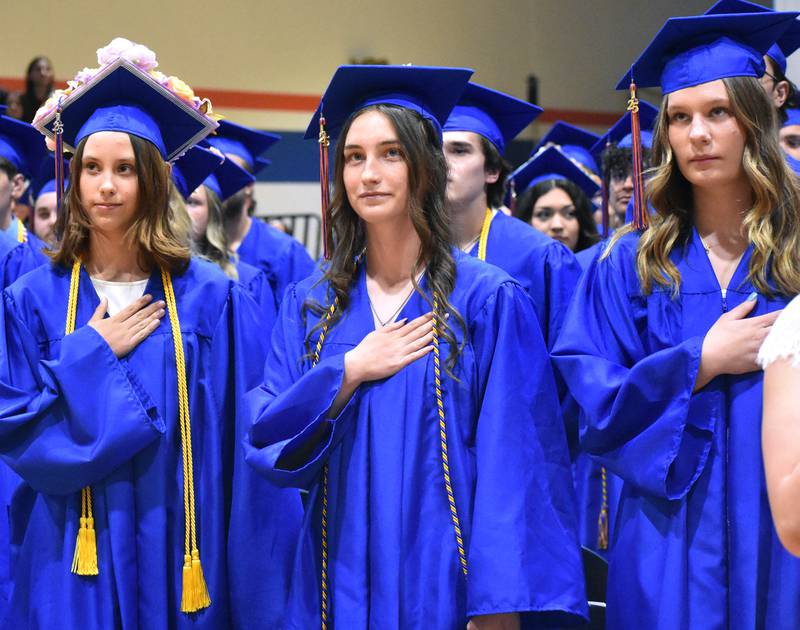 (Left to right) Ava Wells, Samantha Wendt, and Alexis Wille stand for the National Anthem Saturday, May 17, 2025, during Genoa-Kingston High School graduation at the school.