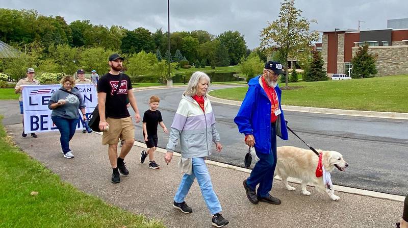 Canines4Christ retriever golden Joey walks with his owners, U.S. Army veteran and Chaplain of the American Legion Post No. 337 Dick Hilderbrant (right), and wife Linda Hilderbrant, of Hampshire, during the inaugural Be the One walk to combat veteran suicide rates. The 2.2-mile trek began at Northwestern Medicine Health and Wellness Center, 626 Bethany Road, DeKalb, and drew a large crowd Sunday, Sept. 22, 2024.