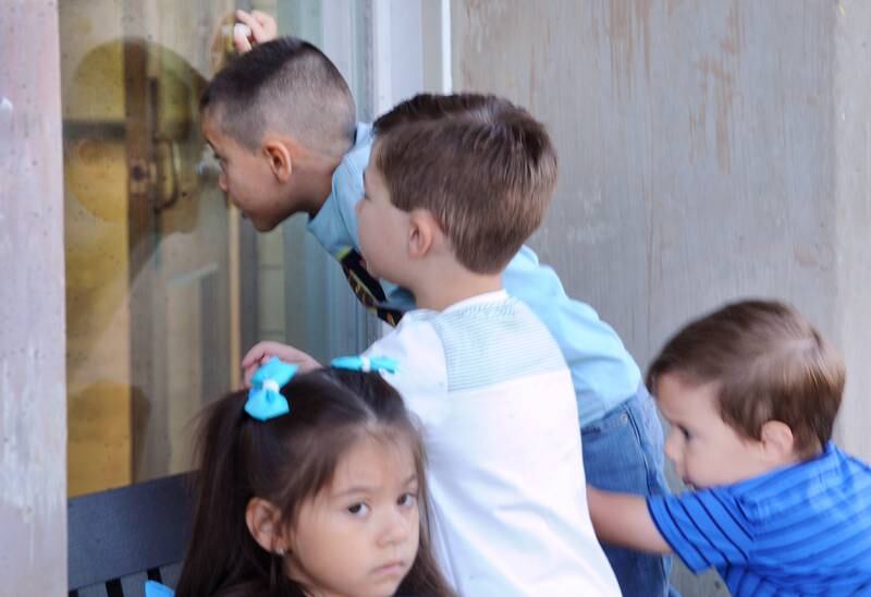 Pre-K boys climb on a bench to take a peek while waiting to check in on the first day of school at Haskin Elementary in Sandwich on Wednesday, Aug. 17, 2023.