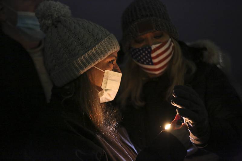 Sheri Schultz (left) and Kathy Belina (right), sister of Ken Kostecki, light candles before a group prayer on Tuesday, Jan. 26, 2021, at Silver Cross Hospital in New Lennox, Ill. Family, friends and coworkers attended a candlelight vigil for Deputy Ken Kostecki of the Will County Sheriffs office who is currently on a ventilator as he battles COVID-19.