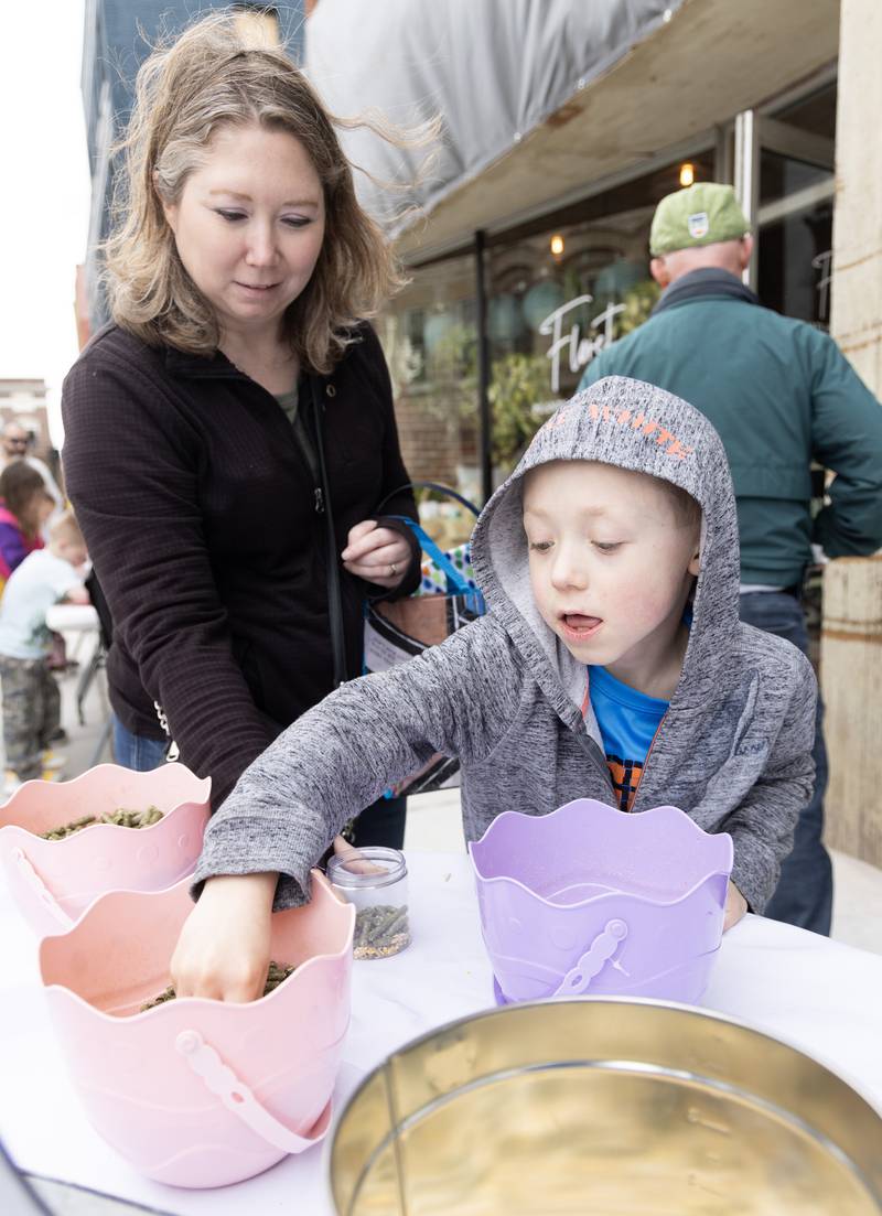 Kyle Durdan, 7, of Grand Ridge, with the help of his mom, Kelly Durdan, creates a mix of food for the Easter Bunny Saturday, March 30, 2024, on Court Street in Ottawa during the Hurray for Spring special event.