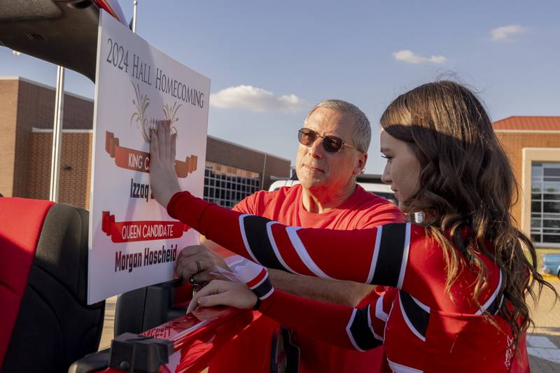 Bob Hoscheid and his daughter Morgan attach a homecoming sign to their vehicle prior to the Hall High School homecoming parade in Spring Valley on September 26, 2024.